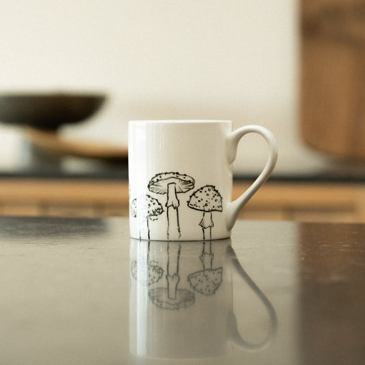 White mug with black illustrations on a reflective surface