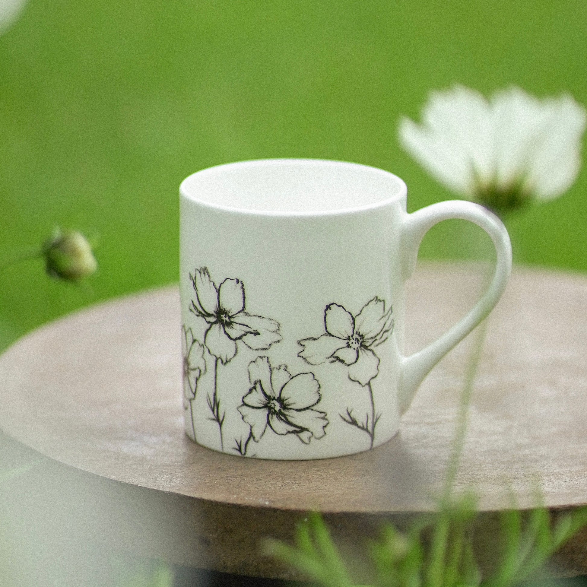 White mug with floral designs on a wooden surface with a natural background