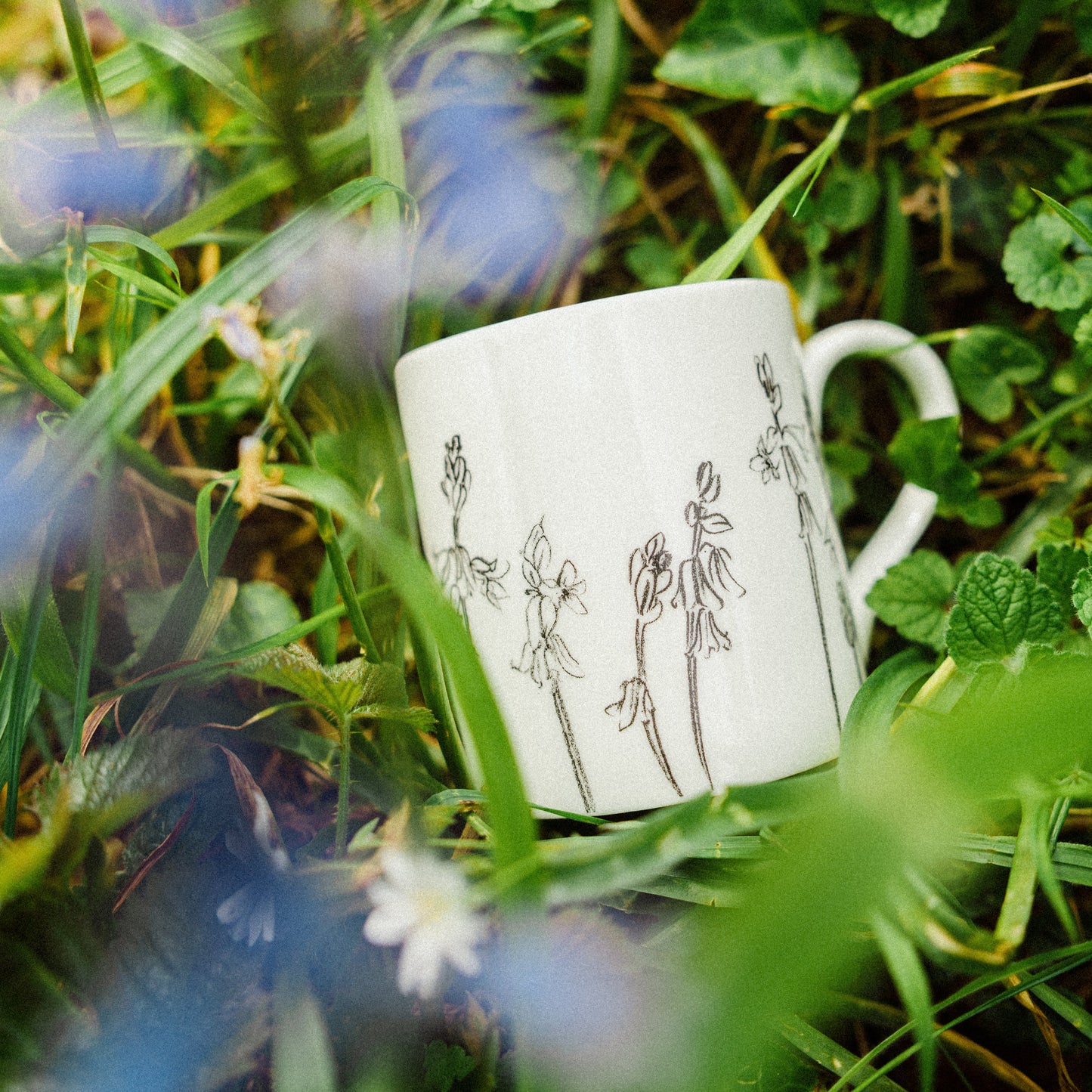 White mug with black illustrations on grass and flowers