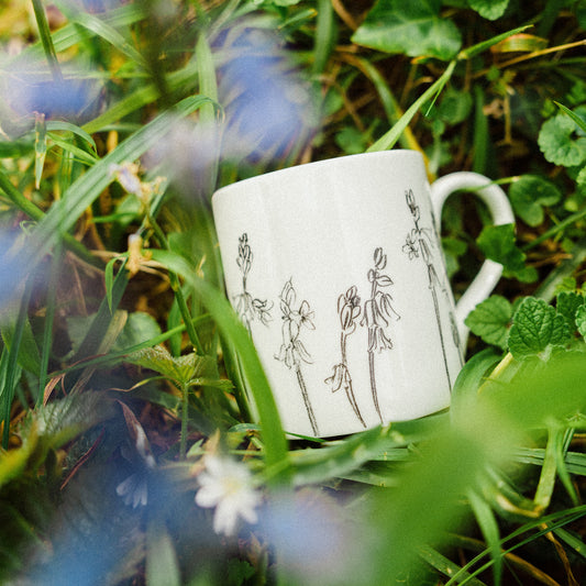 White mug with black illustrations on grass and flowers