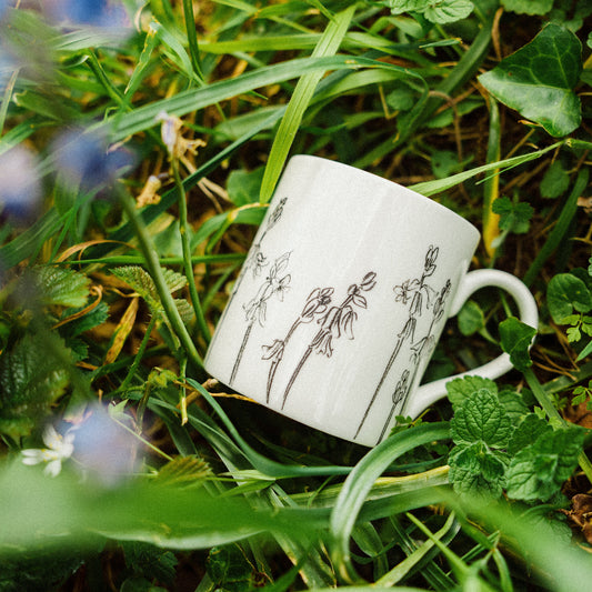 White mug with floral design on grass