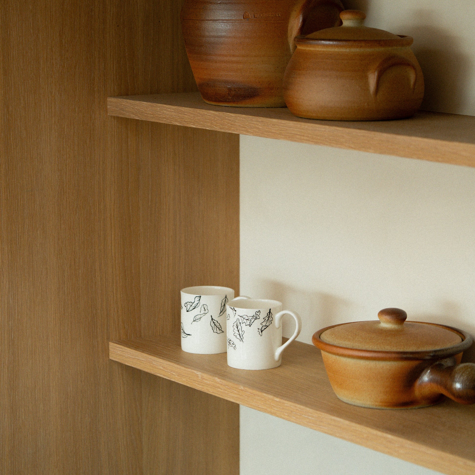 Wooden shelves with ceramic pots and mugs in a home setting