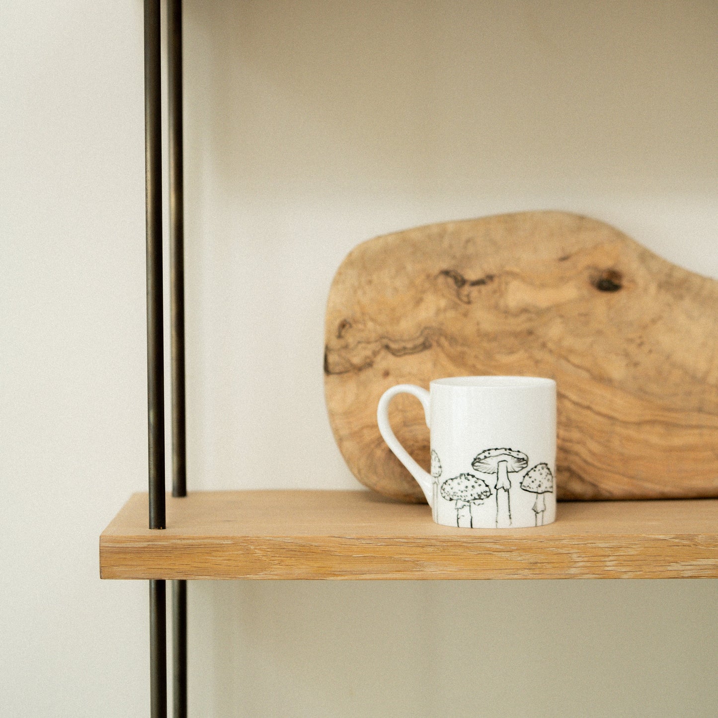 Wooden shelf with a mug and a piece of driftwood against a plain background