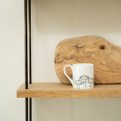 Wooden shelf with a mug and a piece of driftwood against a plain background